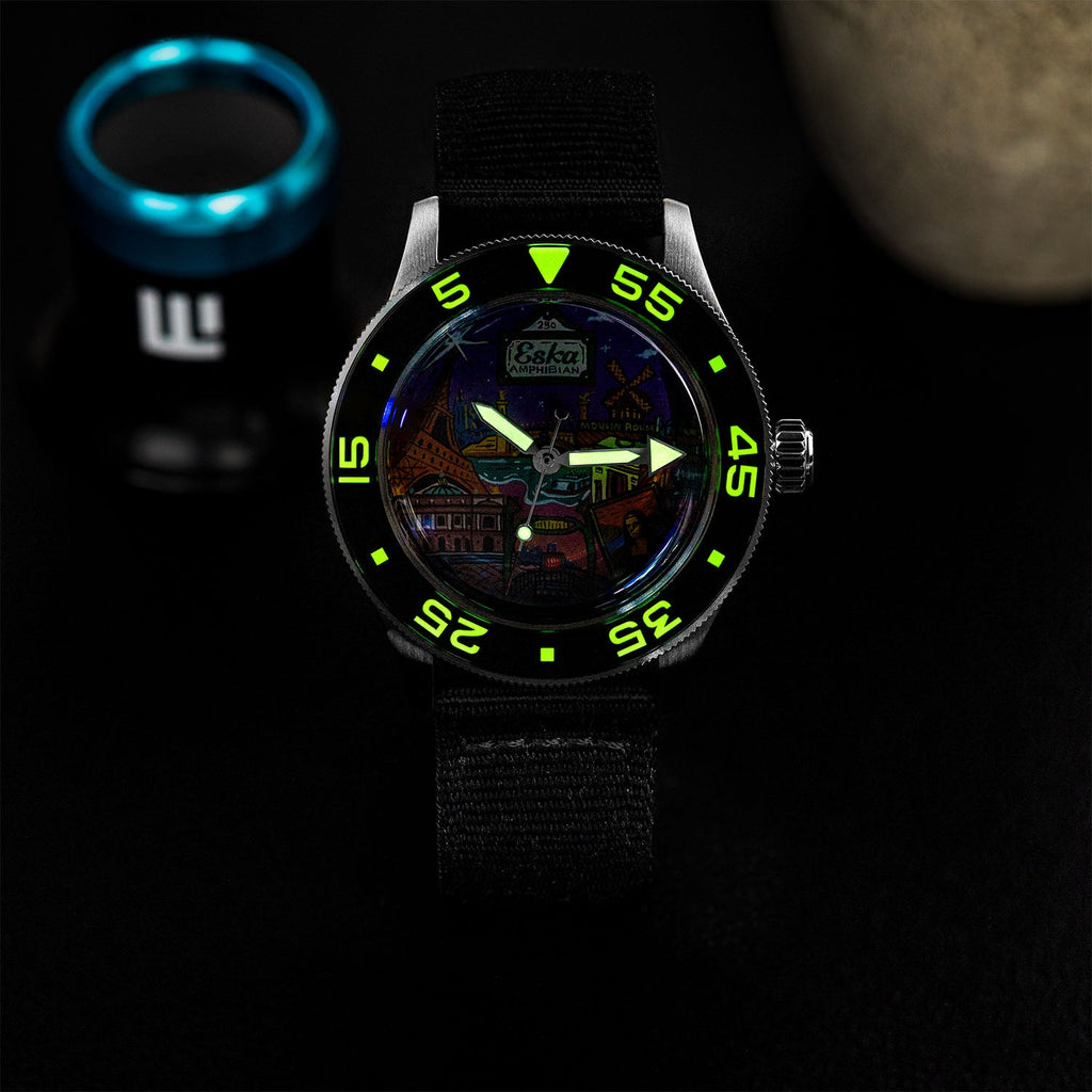 ESKA Amphibian Cœur de Paris — Lume shot in the dark, the dial markers glowing above the hand-painted Parisian cityscape on a 40mm steel diver, customized limited edition by IFL Watches.