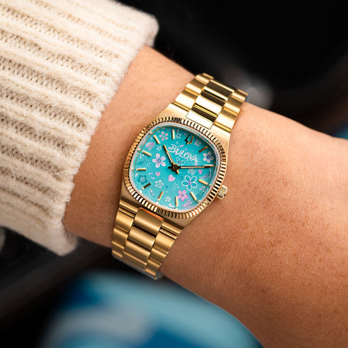 Bulova Super Seville Jardin Bleu — Bespoke 25mm gold-tone watch worn on the wrist, its hand-painted turquoise dial showing loose floral brushwork, customized exclusively by IFL Watches.