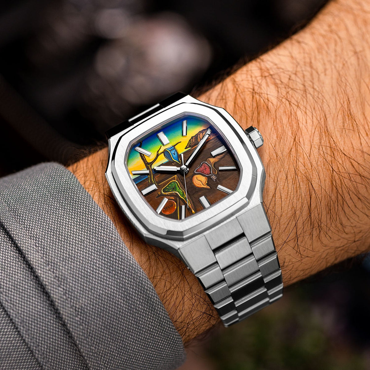MAEN Manhattan Memento — Tilted view on the wrist, the hand-painted custom dial catching the light across its golden cliffs and a blue soft watch hanging from a bare branch, a bespoke timepiece by IFL Watches.