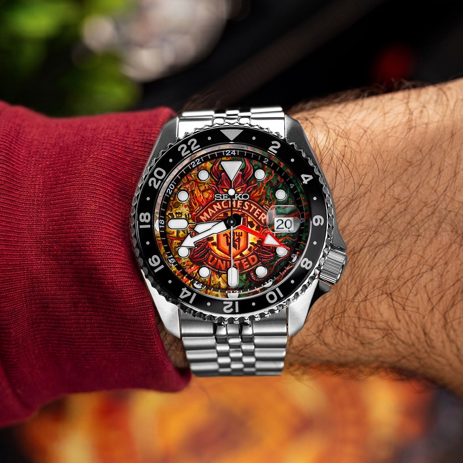 The Red Devils Concept on wrist — close-up of the hand-painted dial showing the fiery football crest with heritage green and golden details, 42.5mm GMT automatic with date window at 3 o'clock, a bespoke timepiece by IFL Watches.