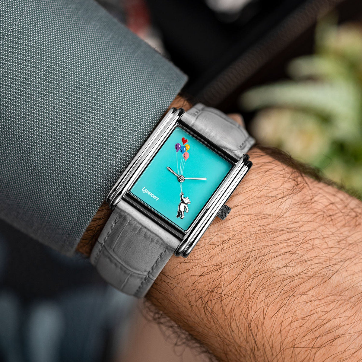 Laphont Bloc Cloudling — Angled on the wrist below a grey shirt sleeve, soft greenery blurred behind the turquoise dial and grey croc-embossed strap, a hand-painted limited edition timepiece by IFL Watches
