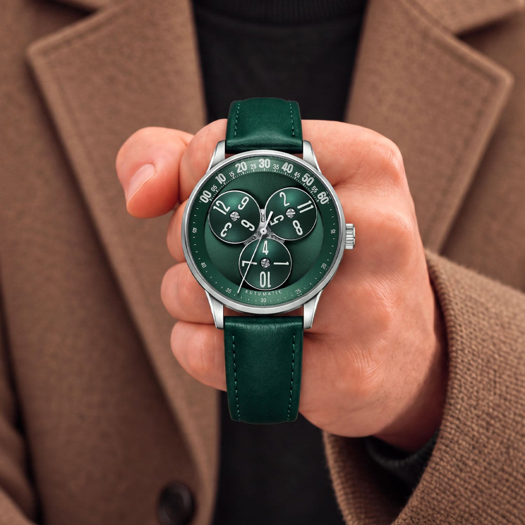 Mandetbrote Wandering Hour Green — Held in hand against a camel coat, showing the hour discs and central seconds hand, available at IFL Watches.