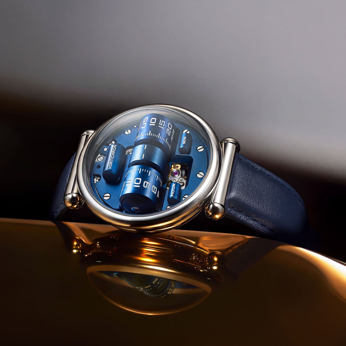 Vortichron Double Roller Blue — Angled on a reflective gold surface, showing the rollers and balance window, available at IFL Watches.